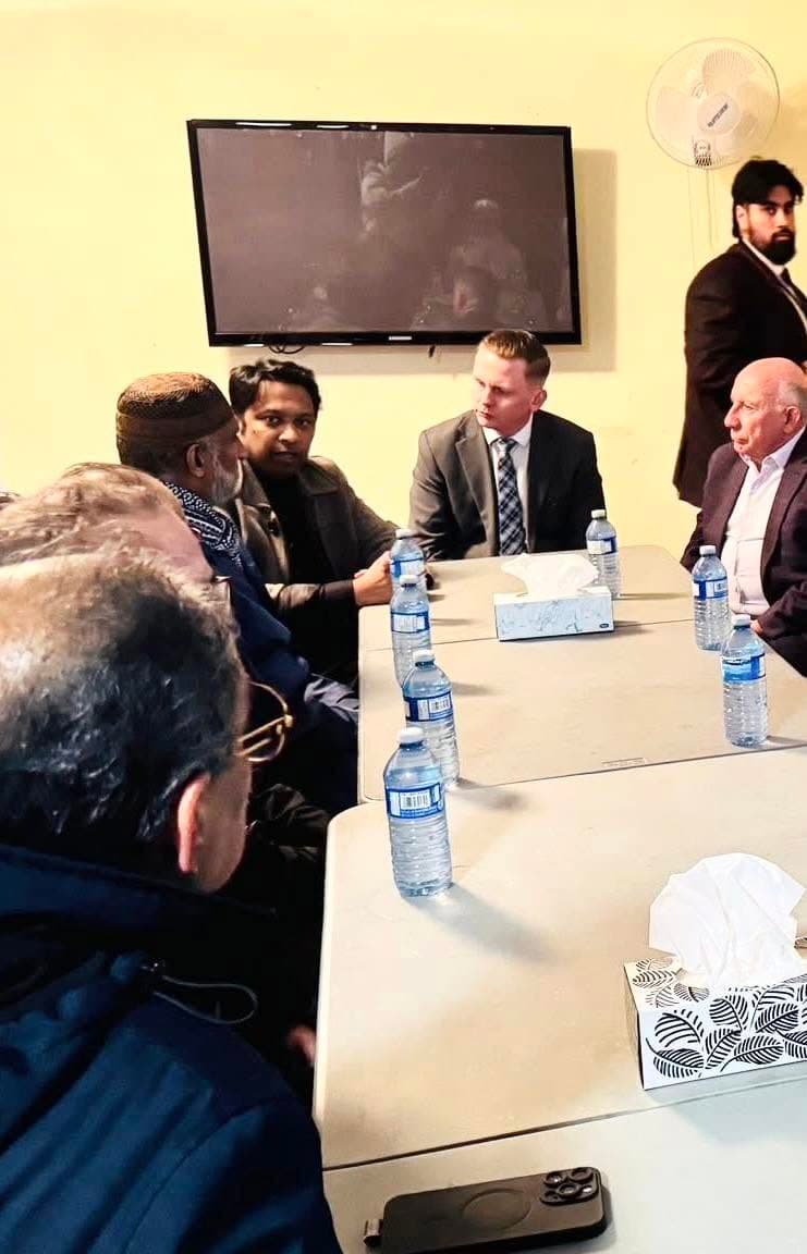 Murshed Nizam seated at a community discussion table with local residents